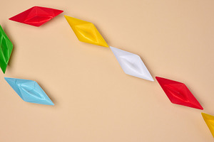 Multi-colored origami paper boats are arranged in a curved line,, a Business Photo by ndanko