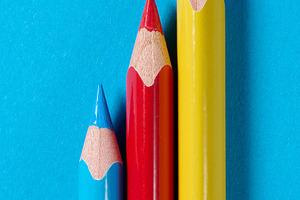 Three colored wooden pencils on a blue background, a School & Education Photo by ndanko