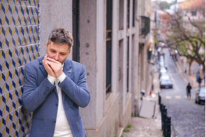 Man plays harmonica outdoors in city