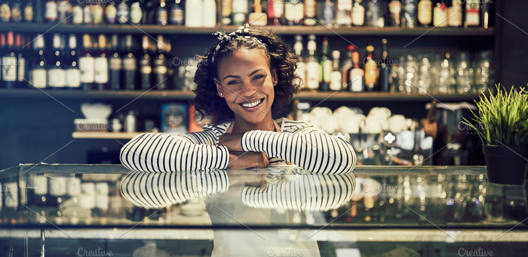Friendly young African cafe owner leaning on a counter, a Business Photo by Stefan & Janni
