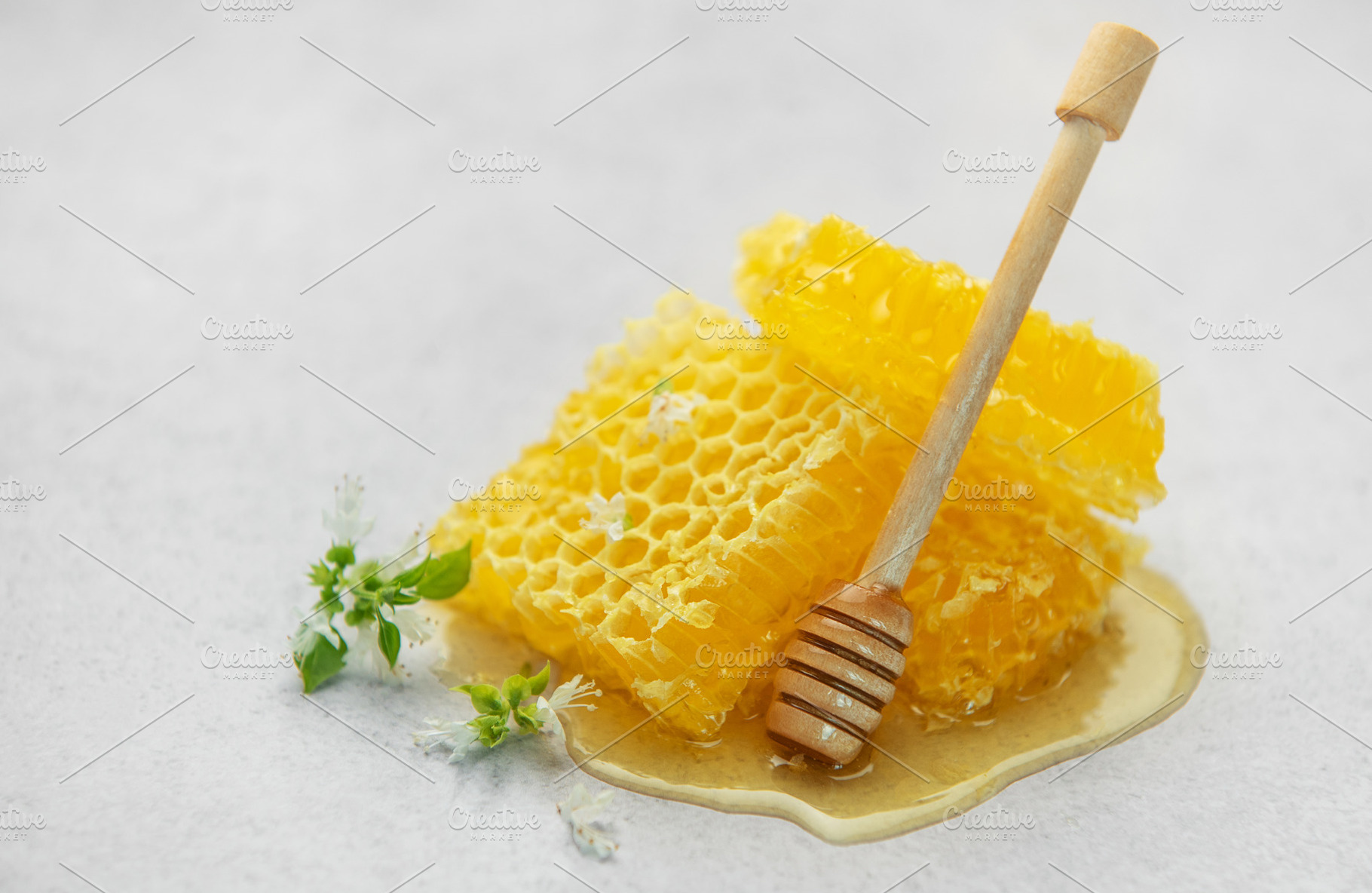 Honeycombs with wooden honey dipper and small white flowers on l, a Food & Drink Photo by Olena Rudo