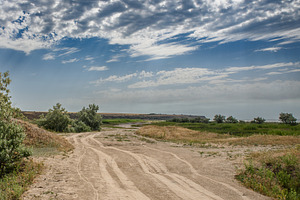 A dirt sand road runs through a flat landscape in the middle of, a Nature Photo by ndanko