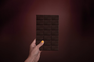 Female hand with yellow nail polish holding a dark chocolate bar, a Food & Drink Photo by Ales Munt