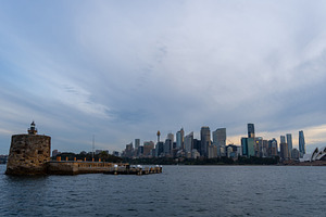 Sydney skyline at sunset with golden reflections on the water, an Architecture Photo by GoodGoods