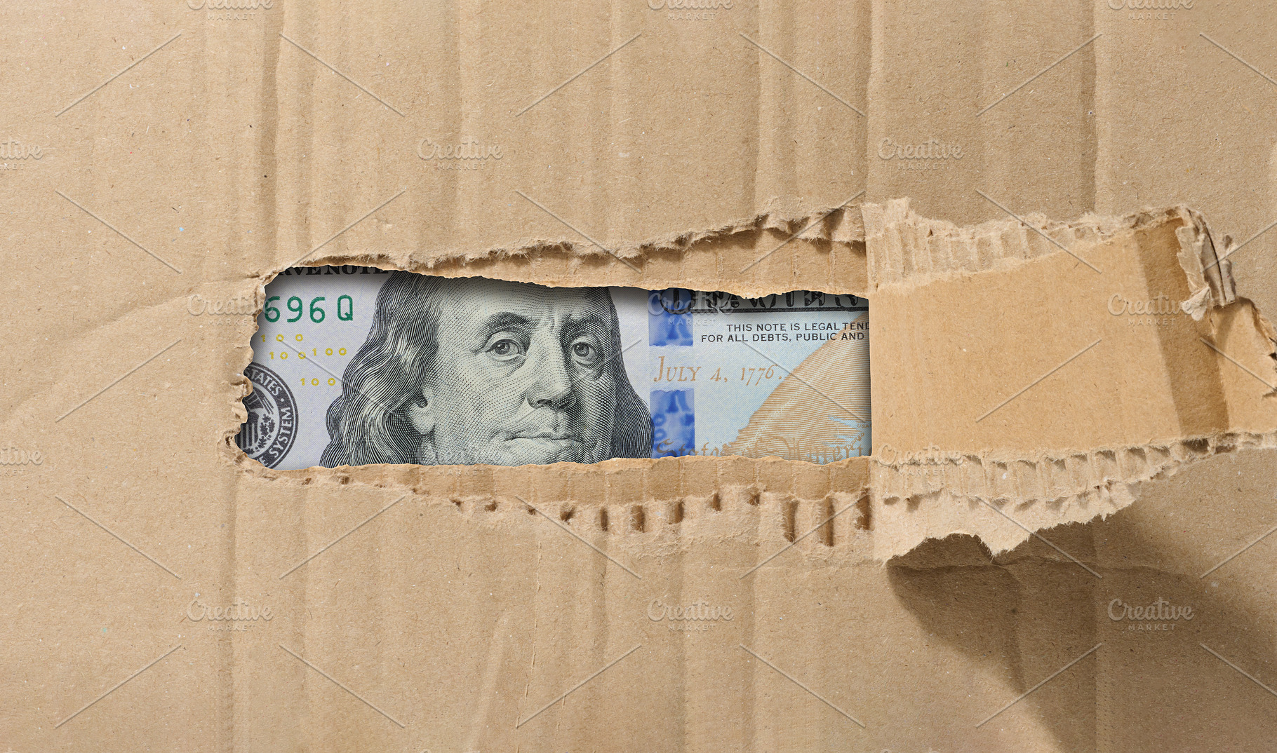 Hundred dollar bill is visible through a hole in the paper., a Business Photo by ndanko