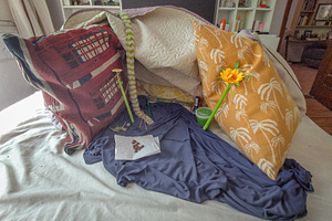 Messy bed with pillows and yellow flower, a Background Photo by DanFLCreativo
