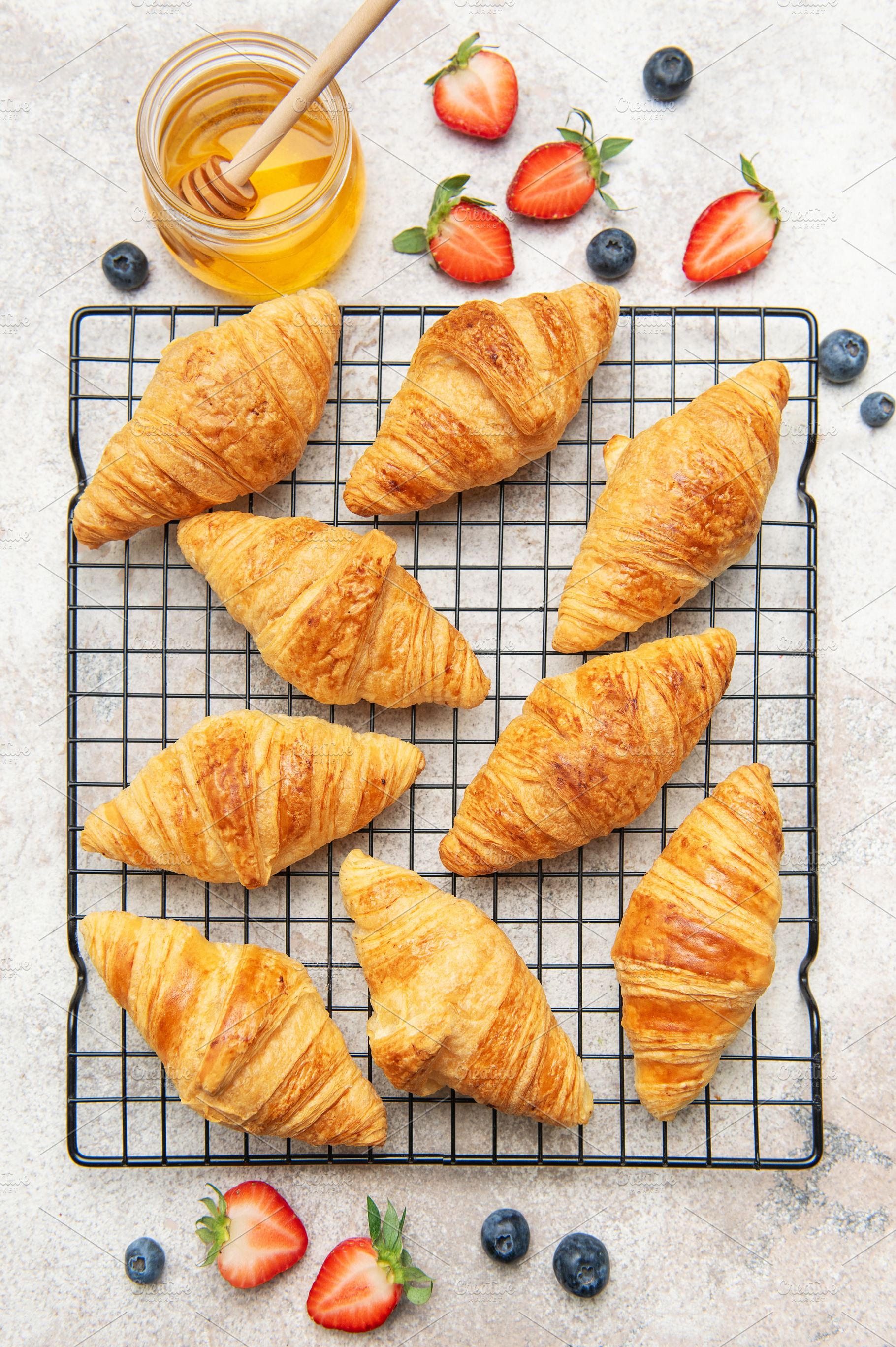 Freshly baked croissants cooling on a wire rack with honey and b, a Food & Drink Photo by Olena Rudo