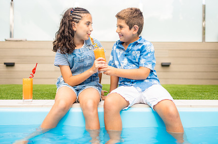 Two little kids sharing an orange juice in the swimming pool, a Person Photo by Cosca