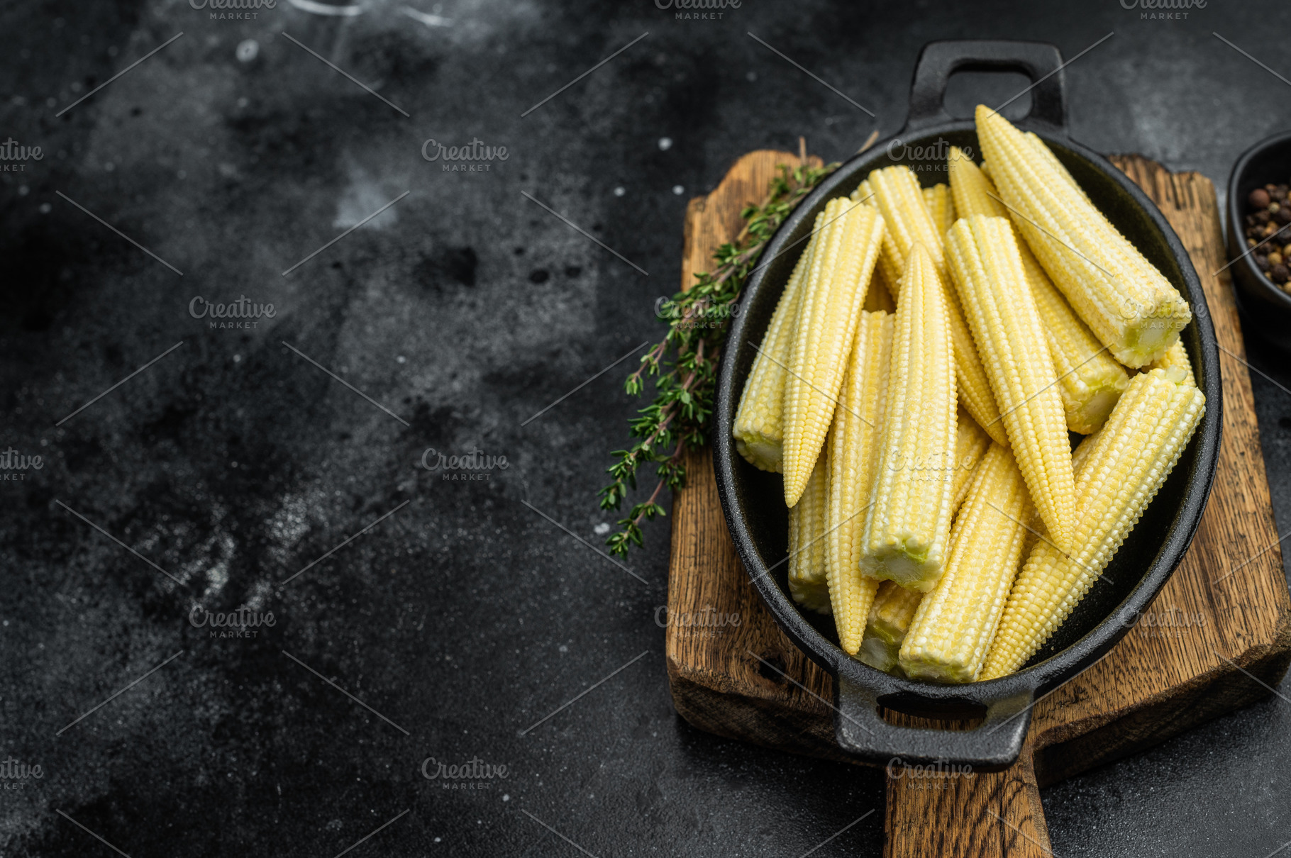 Raw baby corn maize arranged in black skillet top view with thym, a Food & Drink Photo by composter-box@mail.ru