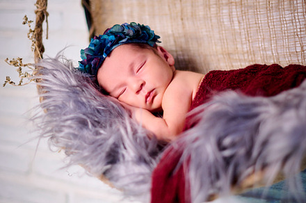 a newborn baby girl, sleeping on a fabric bow with a blue flower headband, a Photo by YossSabalet