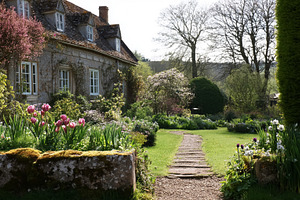 Stone cottage garden in spring, winding path leading through blo, a Photo by Studio ANNA