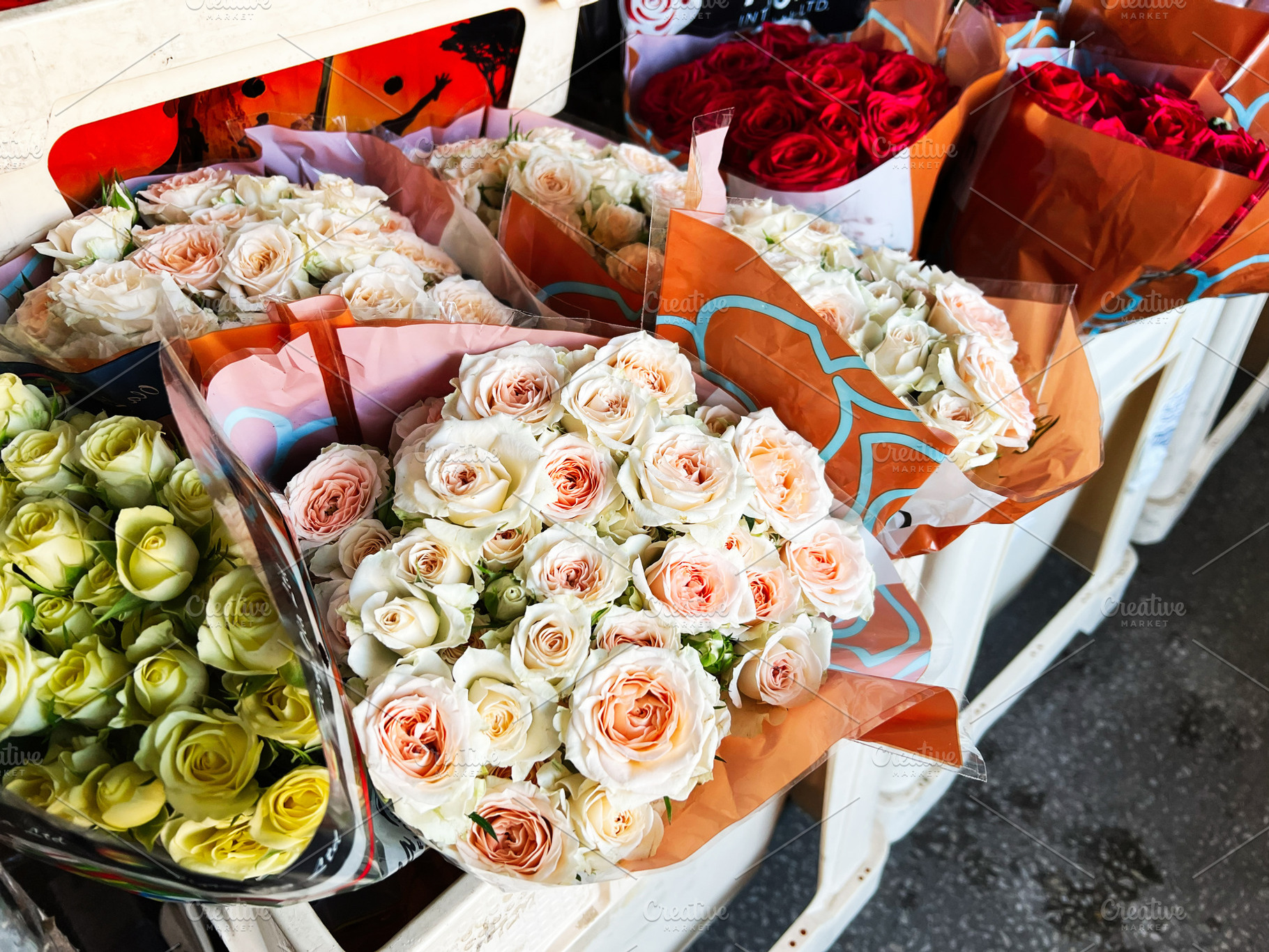 Bouquets of roses displayed for sale at a flower market on a sunny day, a Photo by AS photostudio