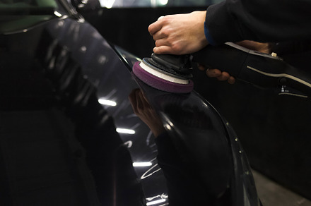 Worker polishes a car’s paintwork, a Photo by borodai94
