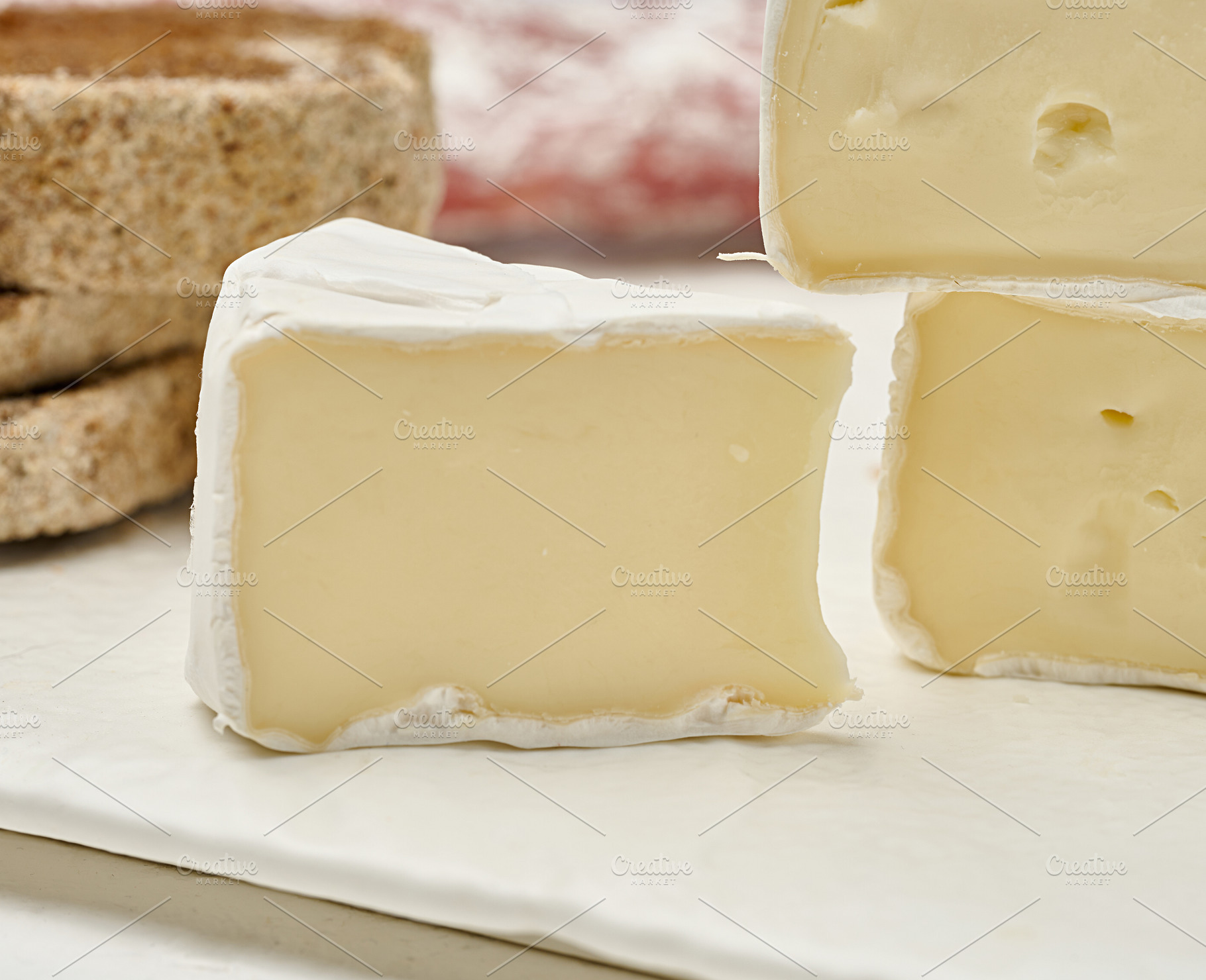 Sliced round head of Camembert cheese on a white board, a Food & Drink Photo by ndanko