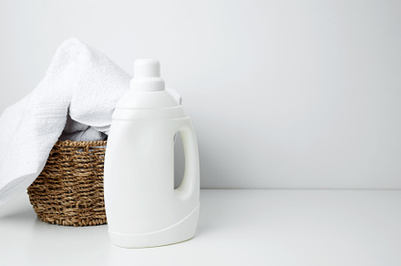Laundry detergent branding mock up and basket filled with clean white towels. H