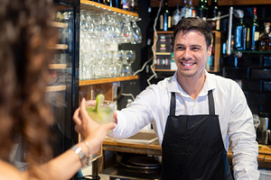 Friendly Bartender Serving a Drink to Female Customer, a Person Photo by etorres69