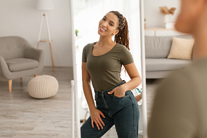 Happy Black Female After Weight Loss Standing Near Mirror Indoor, a Photo by Prostock-Studio