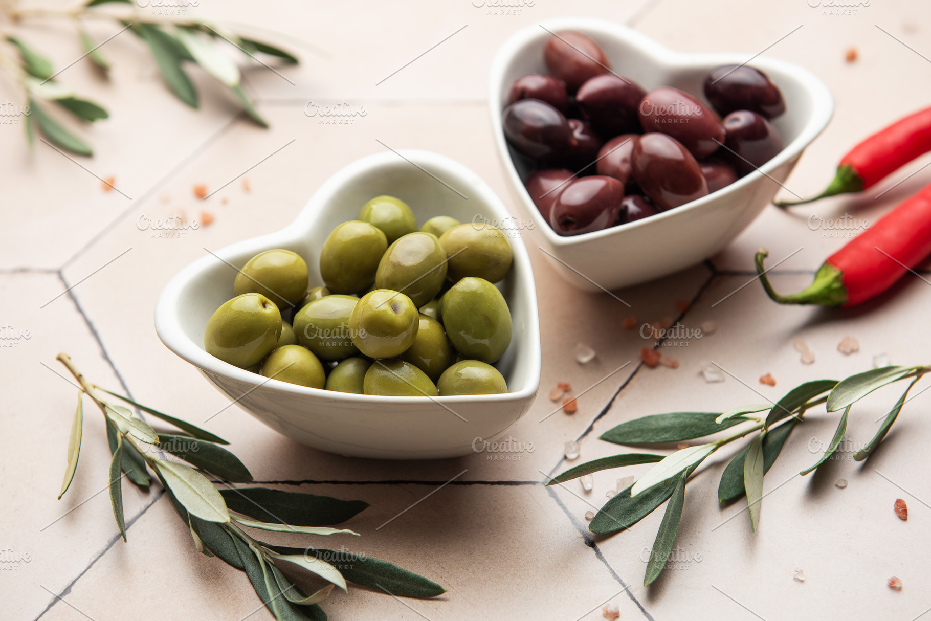 Heart shaped bowls containing green and black olives, olive bran, a Food & Drink Photo by Olena Rudo