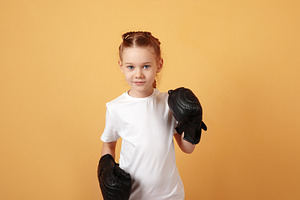 Young girl in white t-shirt with black boxing gloves stands read, a Person Photo by Ales Munt