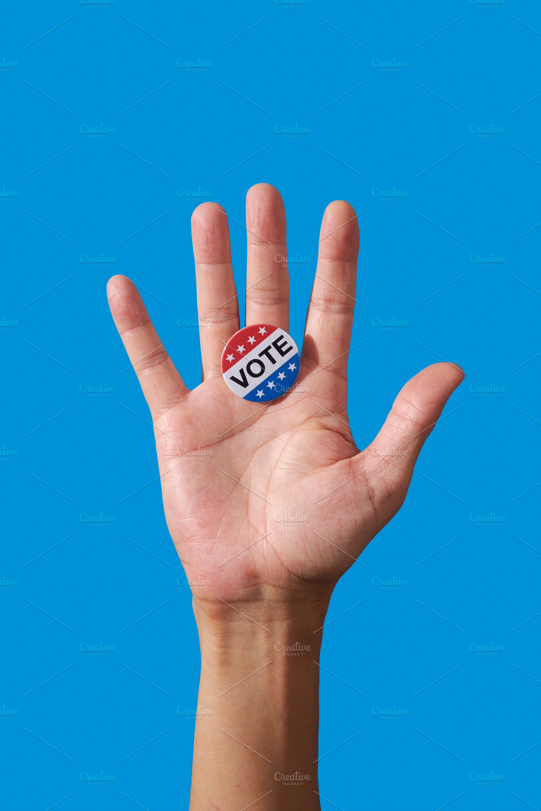 man displaying vote badge on open palm, a Photo by Nito