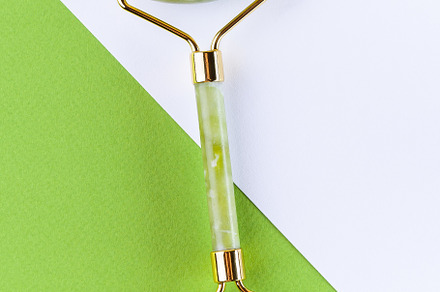 Green jade facial roller and massage on colorful background, vertical, top view, a Health & Medical Photo by iuliia_n