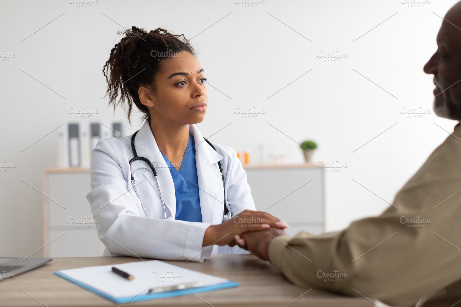 Close up of black female doctor holding male patient's hands, a Photo by Prostock-Studio