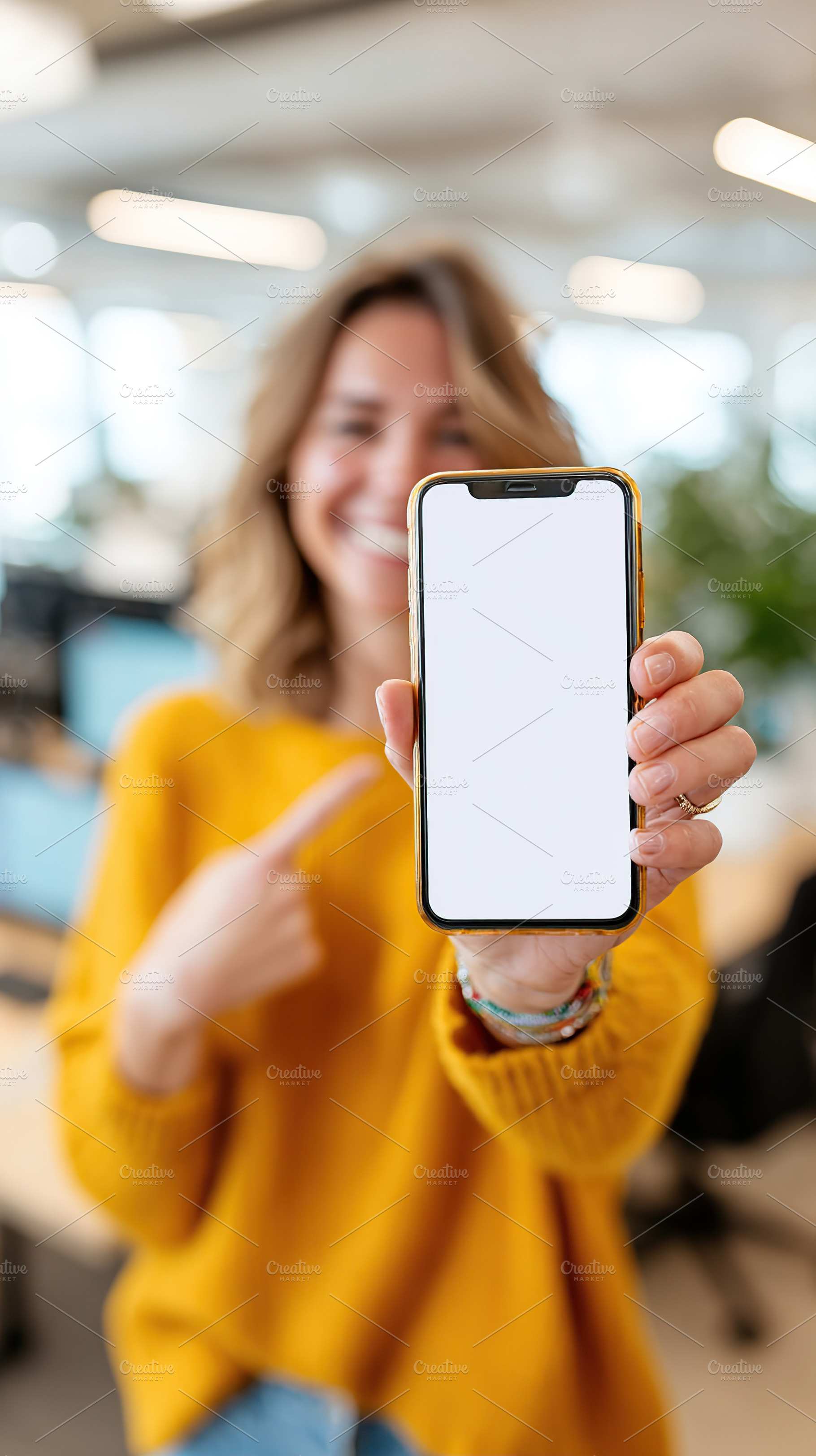 Woman showcases blank smartphone screen in a modern office setting during work, a Person Photo by AlyaAnd
