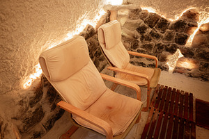 Comfortable chairs in a cozy salt room with textured walls and subtle lighting, a Photo by AS photostudio