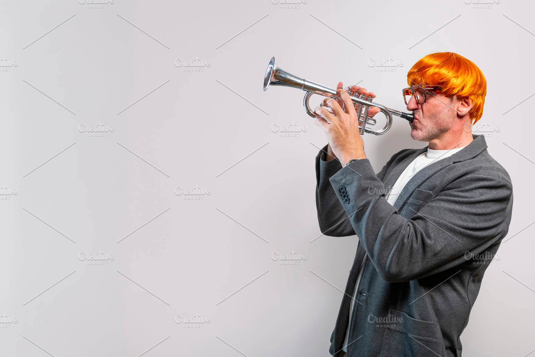 Man wearing orange wig playing trumpet, a Person Photo by karrastock