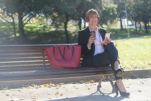 Businesswoman relaxing with coffee and smartphone, a Photo by RF Images