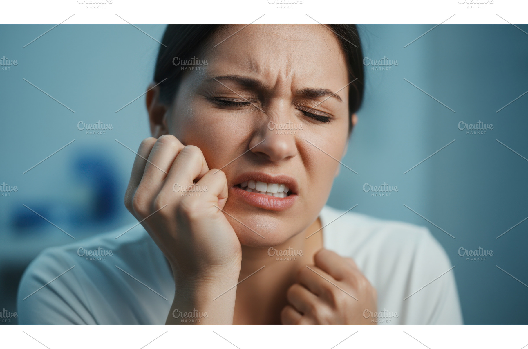 Young woman wincing in pain while, a Health & Medical Photo by Igor Tichonow