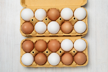 Egg boxes with eggs on white wooden background, a Food & Drink Photo by AtlasStudio PRO