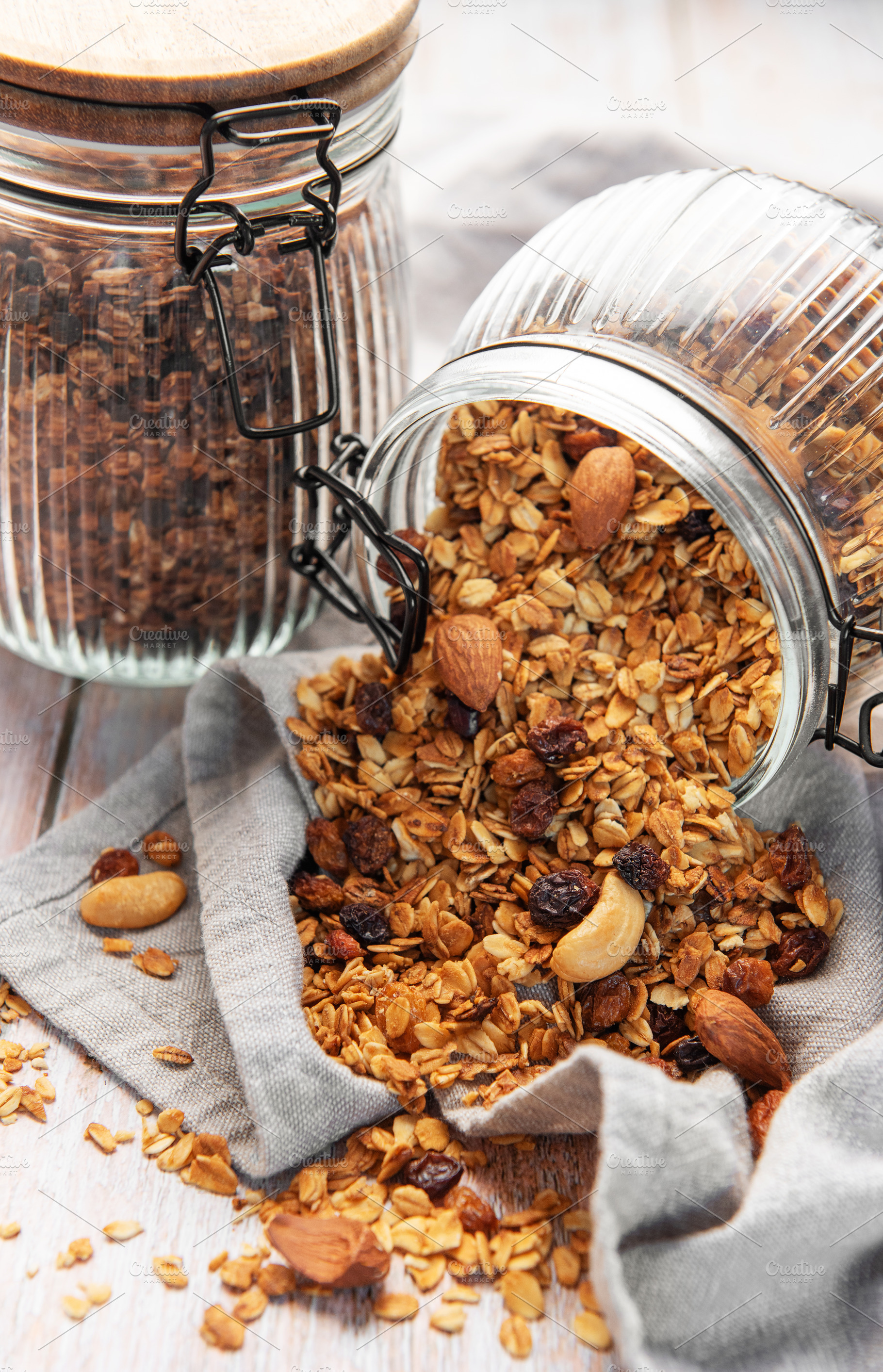 Granola mix with oats, nuts, and dried fruits spilling onto a gr, a Food & Drink Photo by Olena Rudo