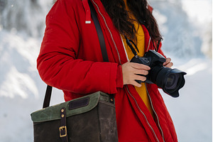 Woman holding camera during winter, a Beauty & Fashion Photo by HalfPoint