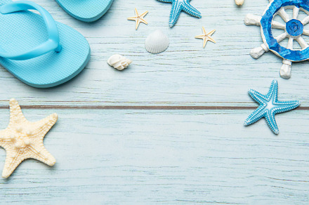 Summer accessories creating a frame on light blue wooden backgro