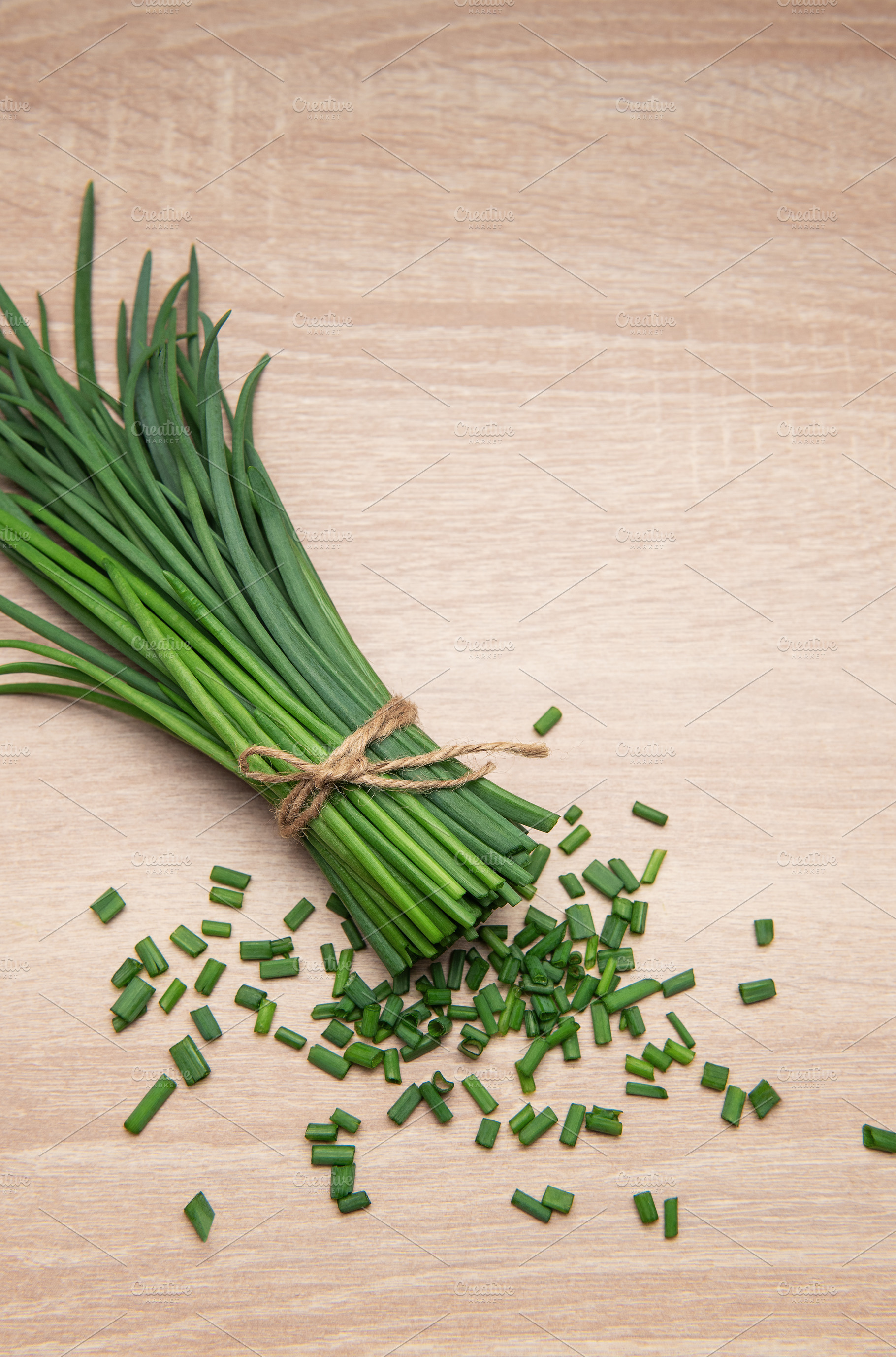 Freshly cut chives tied with twine on wooden table, a Photo by Olena Rudo