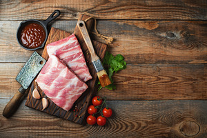 Raw pork ribs with spices, salt and rosemary on dark wooden background, a Food & Drink Photo by Budarinphoto