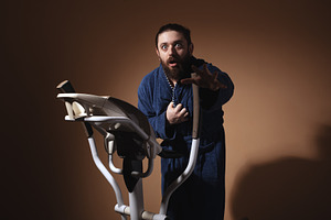 Surprised man in a blue bathrobe using an exercise bike against, a Person Photo by Ales Munt