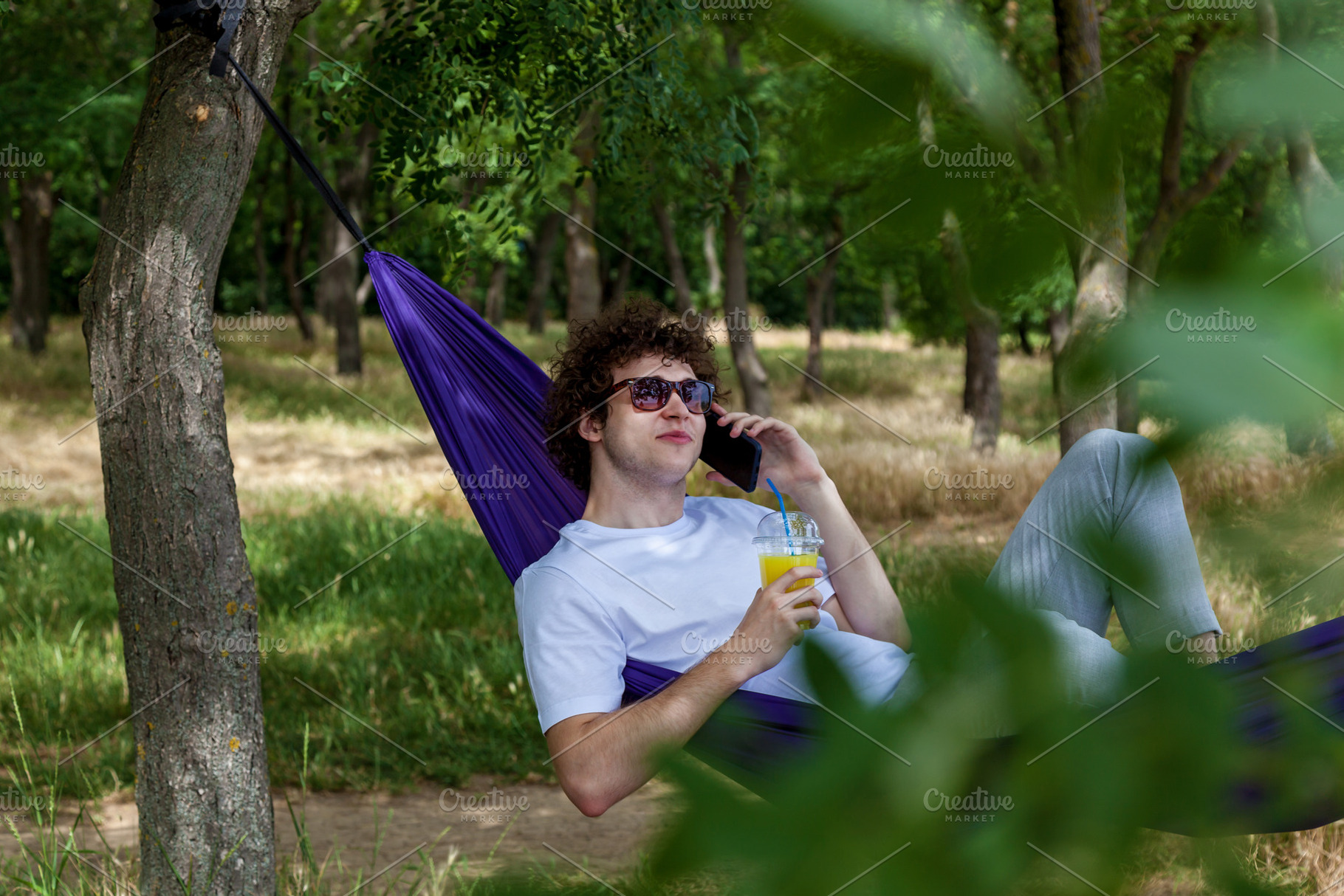 A young guy with curly hair is relaxing on a hammock on a hot summer day., a Person Photo by Photostock