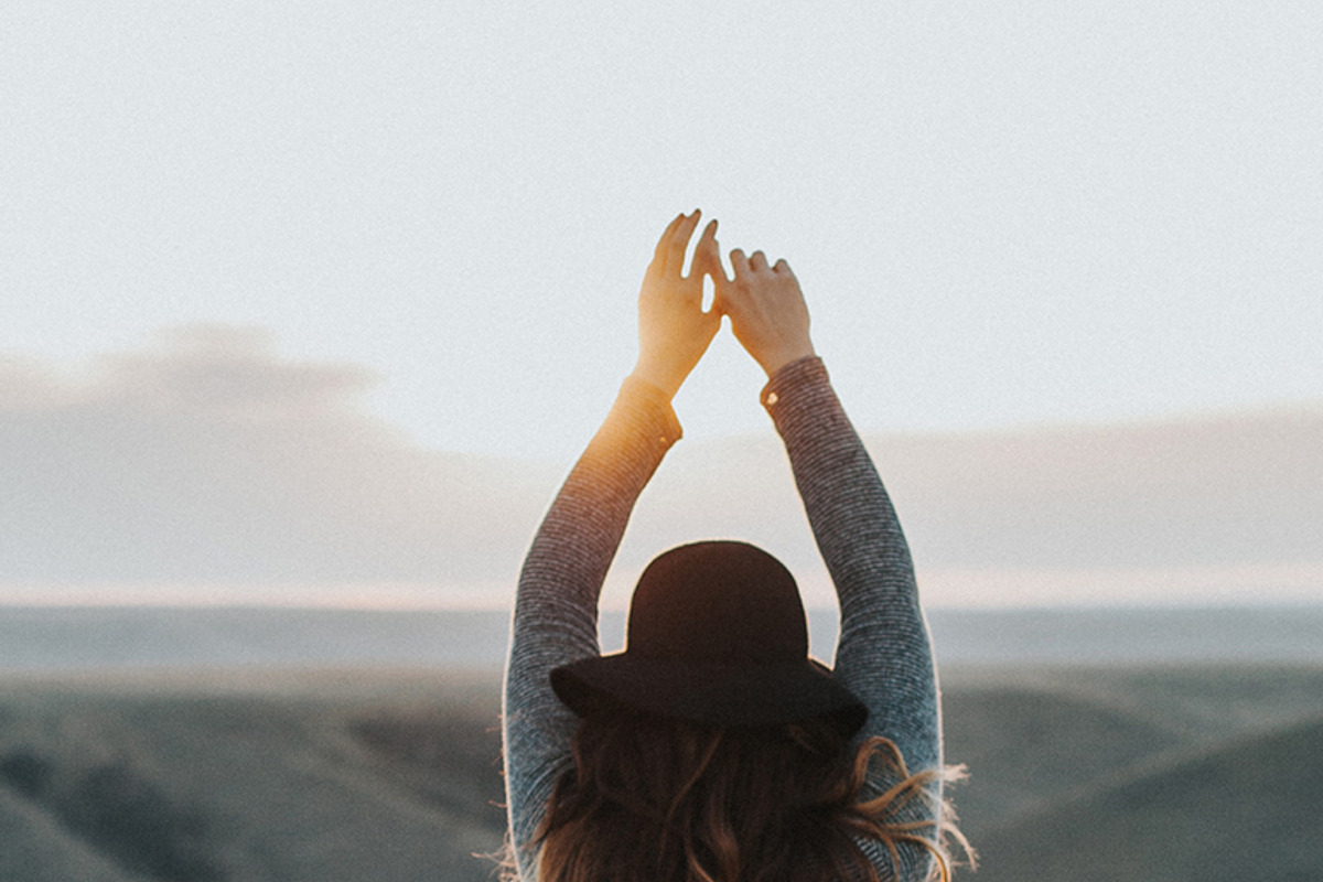 Woman with arms raised at sunset, a Person Photo by Wild Wander Collective (Photo 1 of 2)