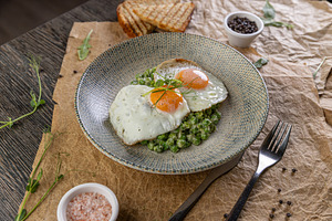Plate of fried eggs on green peas puree, a Photo by Grafvision photography