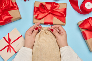 Female hands in a white sweater tightening a jute bag surrounded, a Holiday Photo by ndanko
