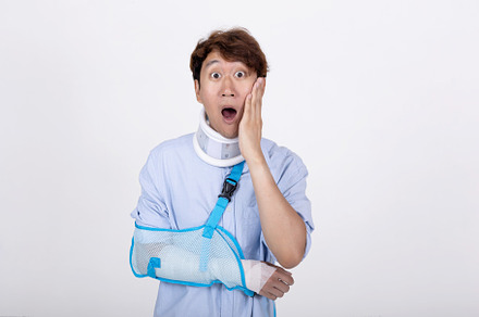 Asian man with broken arm and neck feeling surprised and shocked
