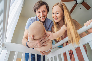 Mother and father lifting baby from, a Person Photo by Elizaveta Galitskaya