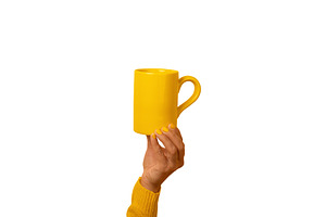 A hand in a yellow sleeve holding a bright yellow ceramic mug ag, a Food & Drink Photo by Ales Munt