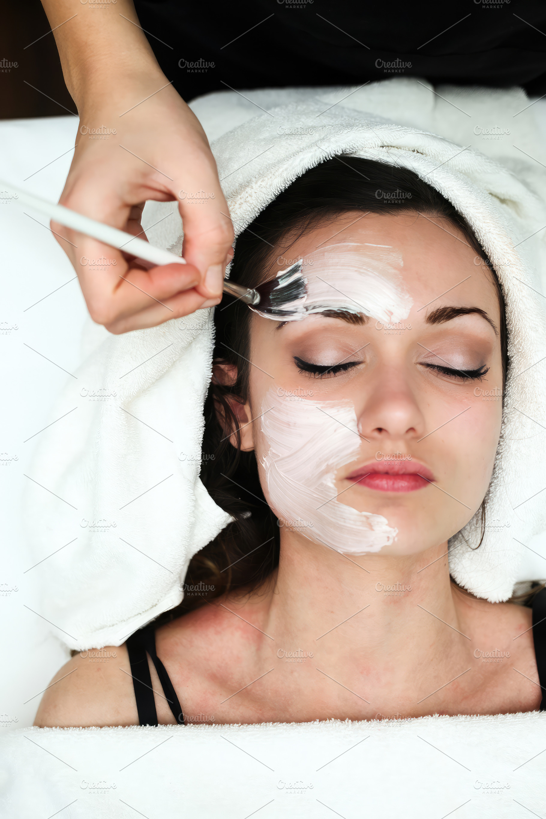 Beautician applying a facial mask with a brush in a spa, an Abstract Photo by Antonio Gravante Market