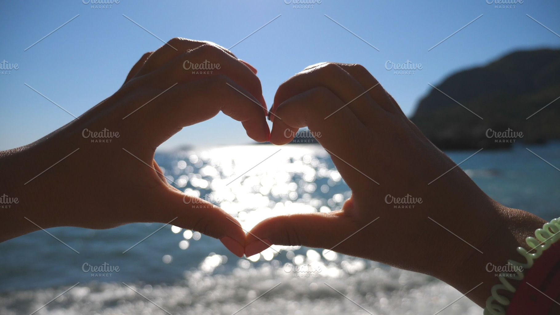 Young girl making heart shape with her hands over sea background on a sunny day. Summer holidays on the beach. Concept of vacation. Close up, a Person Photo by Footage Autor