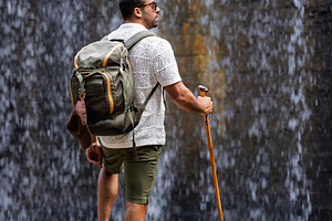 Explorer observing a waterfall from, a Person Photo by Perpis