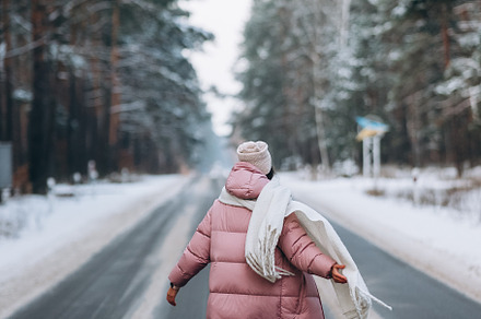 Portrait of a beautiful caucasian woman on a road through snowy forest