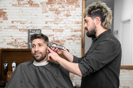 Man barber cutting hair of male client with clipper at barber shop. Hairstyling, a Person Photo by david.herraez.calzad